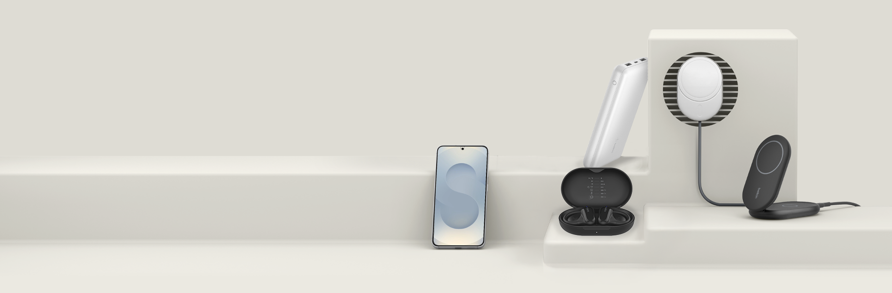 Collection of Samsung accessories by Belkin, including a screen protector, headphones, power banks, a magnetic car charger, and foldable wireless chargers, displayed on a neutral platform with a minimalist design.